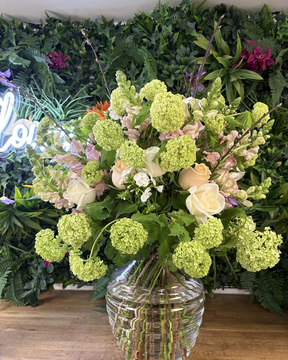Large vase arrangement of green hydrangea and roses