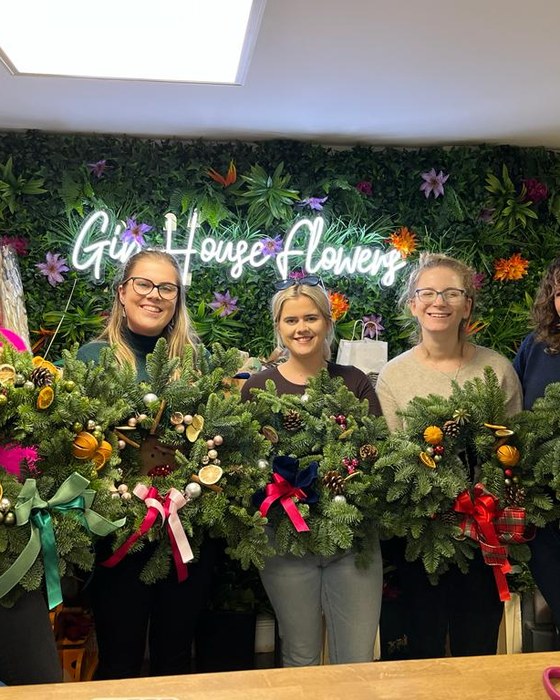 Three guests holding their Christmas wreaths