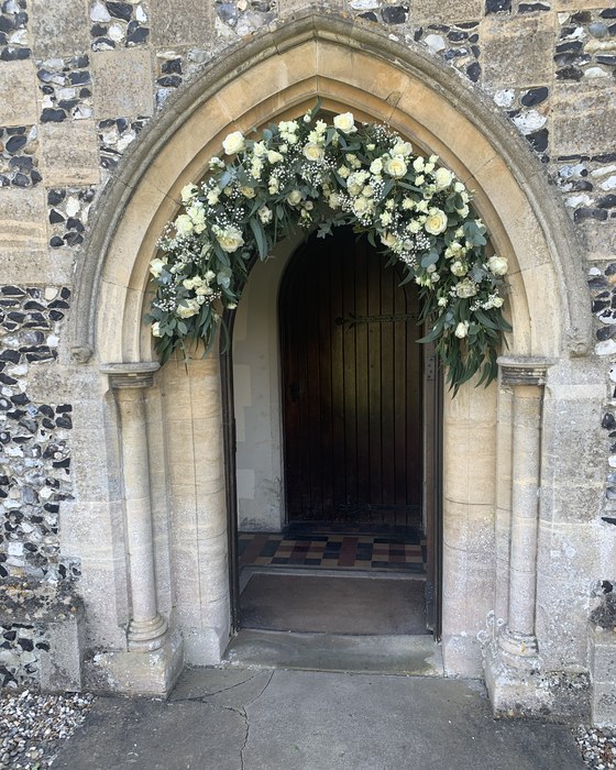 Church doorway framed with white flowers and foliage